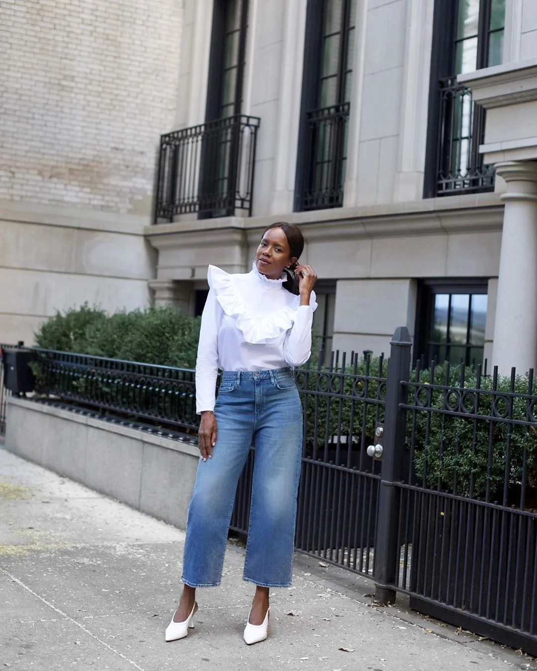 Elaine Davis in a white blouse with a decorative front, cropped wide-leg blue jeans and white pointed shoes.