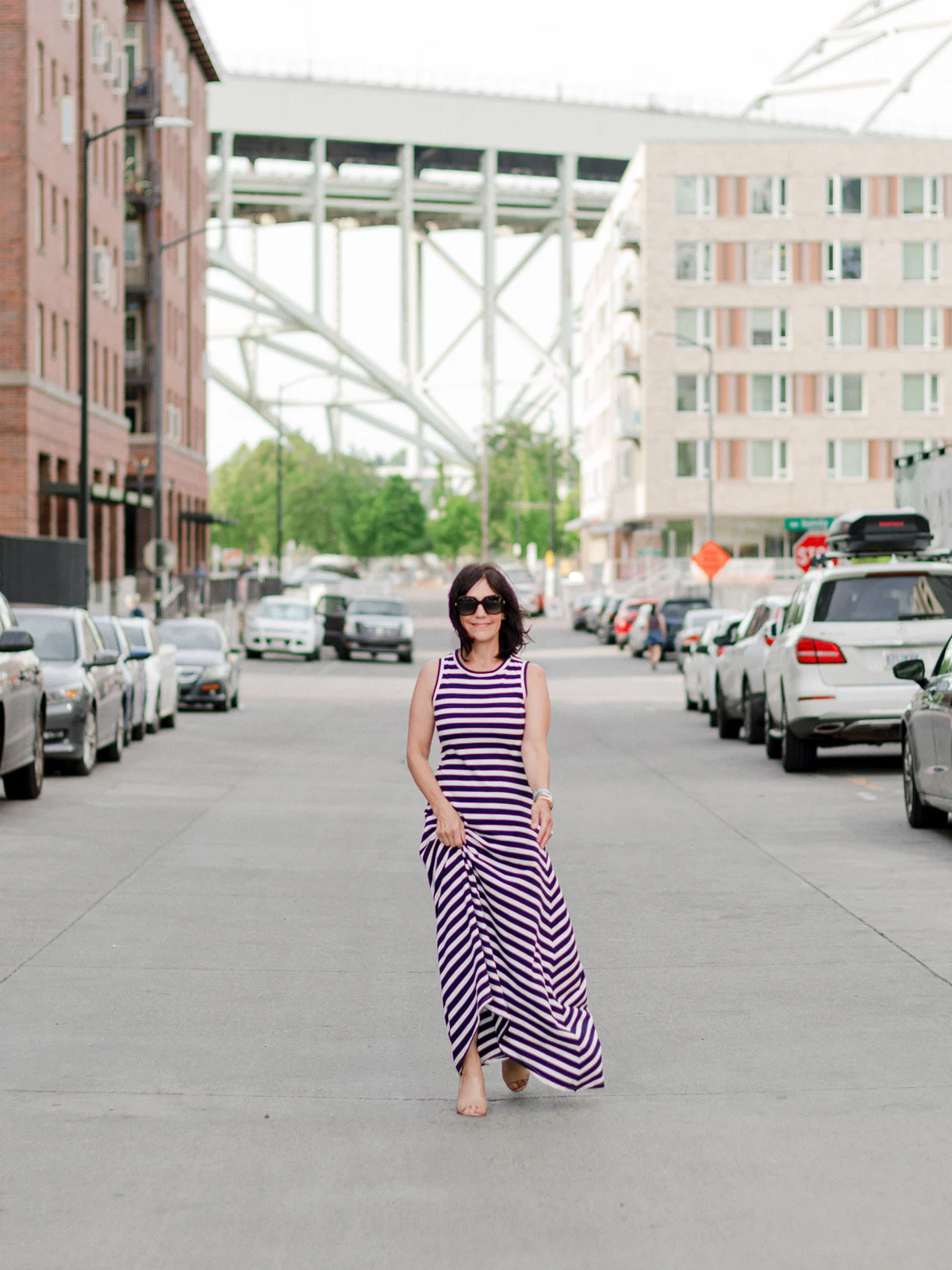 Susie Wright wearing a sleeveless striped maxi dress with a fitted upper half and a flowing hem.
