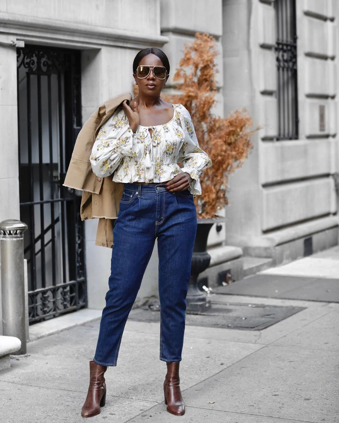 Elaine Davis wearing a pale floral blouse, dark blue jeans, brown ankle boots and a tan jacket over one shoulder.