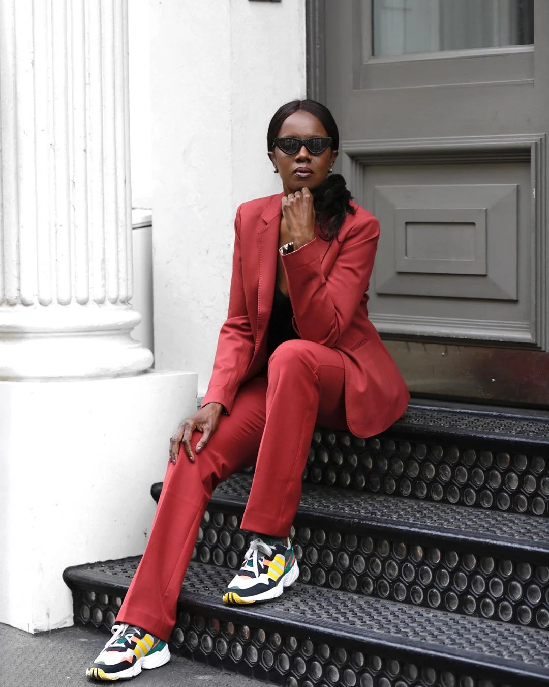 Elaine Davis seated in a red trouser suit with a patterned top and multicolored sneakers.